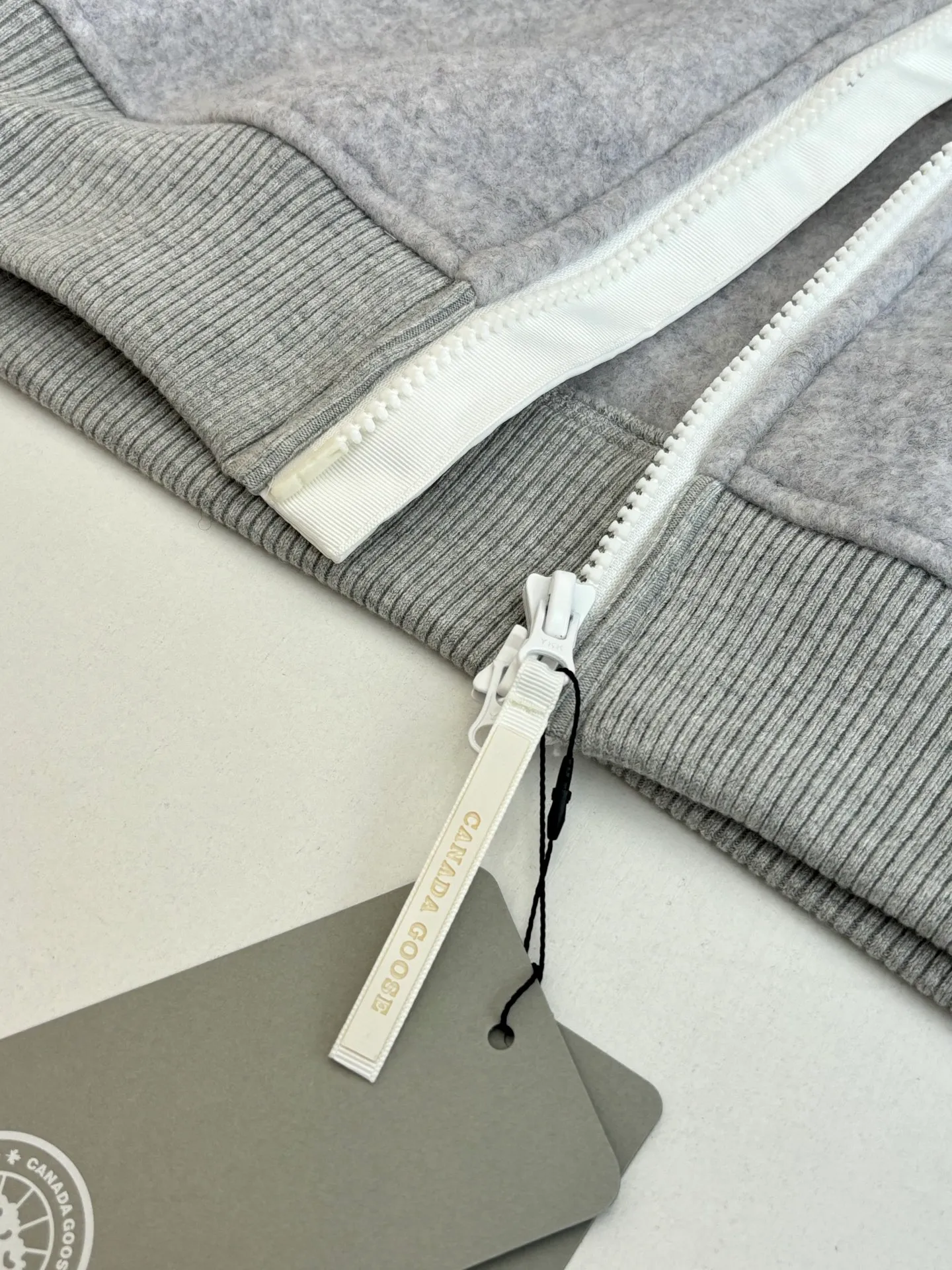 P810 Canada Goos*/Big Goose Fleece Badge Hooded Jacket The fabric is made of wool as the main body, with a very small amount of spandex and polyester fiber blended into the wool fleece fabric. The sleeves and hem are closed with 2×2 ribbing. Its strong elasticity can closely fit wrists and waists of different thicknesses, forming an effective 'seal' to prevent cold wind from blowing back. It can still maintain its original shape after repeated stretching and use, and is not easy to loose and deform. And the ribbed cuffs can convey a sense of design and enhance the visual beauty.  Size：S/M/L/XL